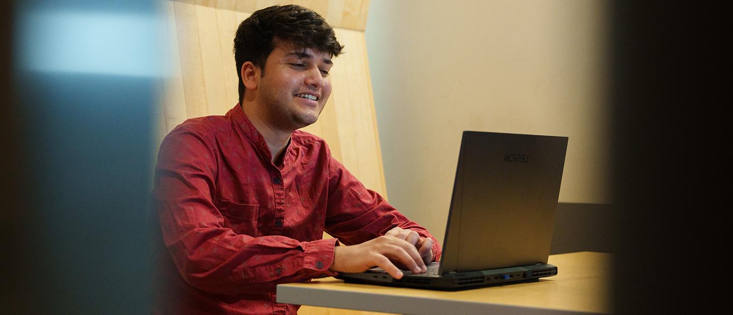 A young man seated, working on a laptop